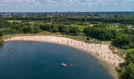 Luchtfoto van mensen die verkoeling zoeken in en op het water.